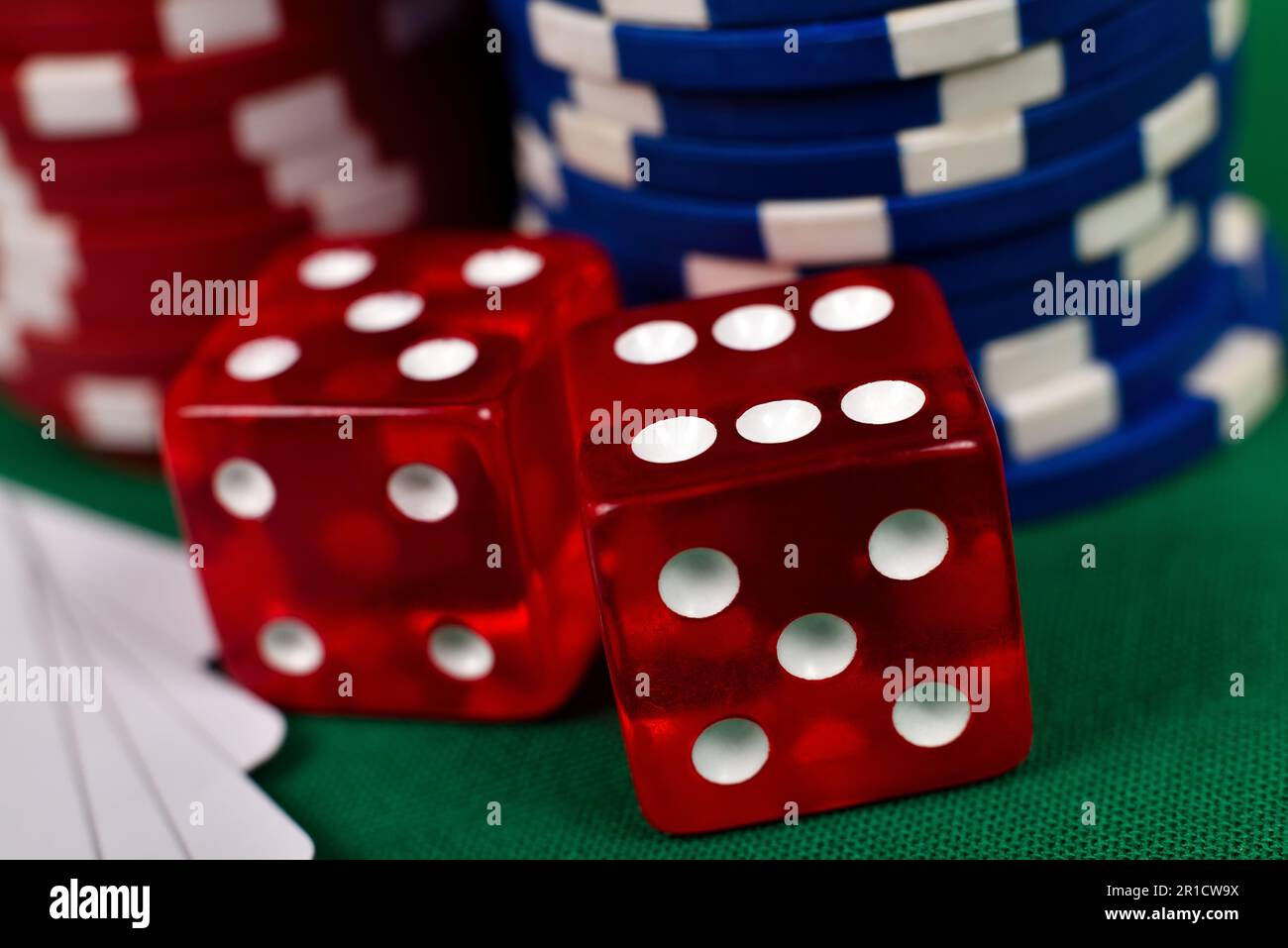 two red dice and poker chips on green table, close up Stock Photo