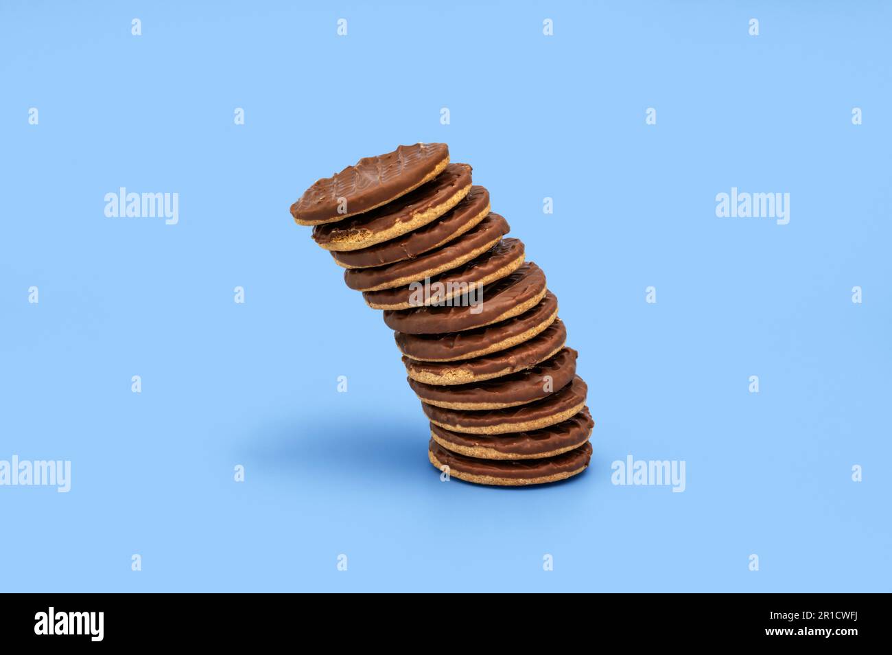 Stacked chocolate biscuits on plain blue background Stock Photo