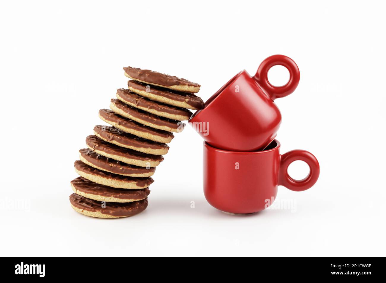 Stacked chocolate biscuits leaning in to two red espresso cups Stock Photo