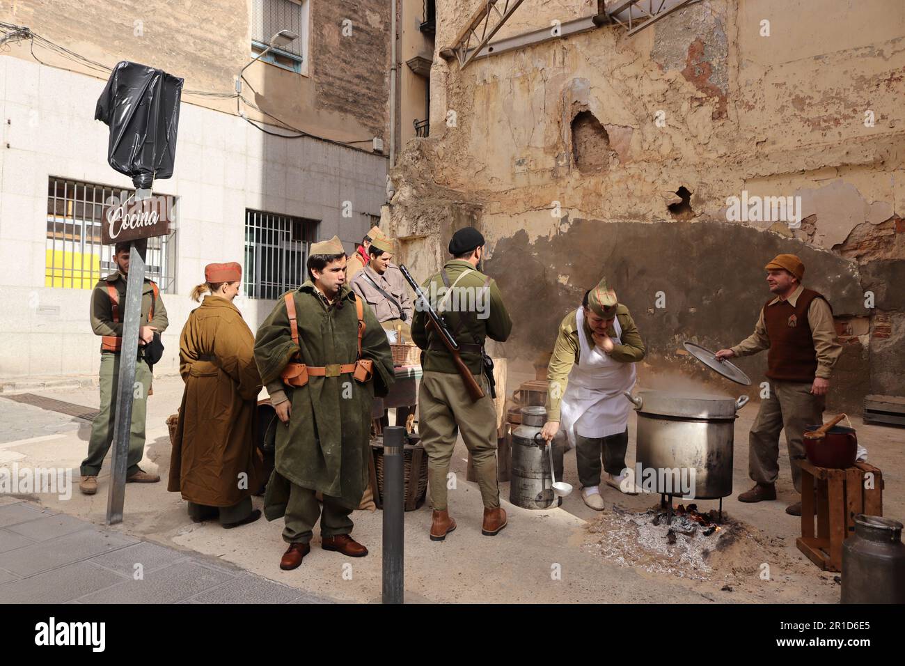 Spanish Civil War reenactment. Living historians recreate a kitchen at the rearguard, with cooks and soldiers. Hunger during war was lethal. Stock Photo