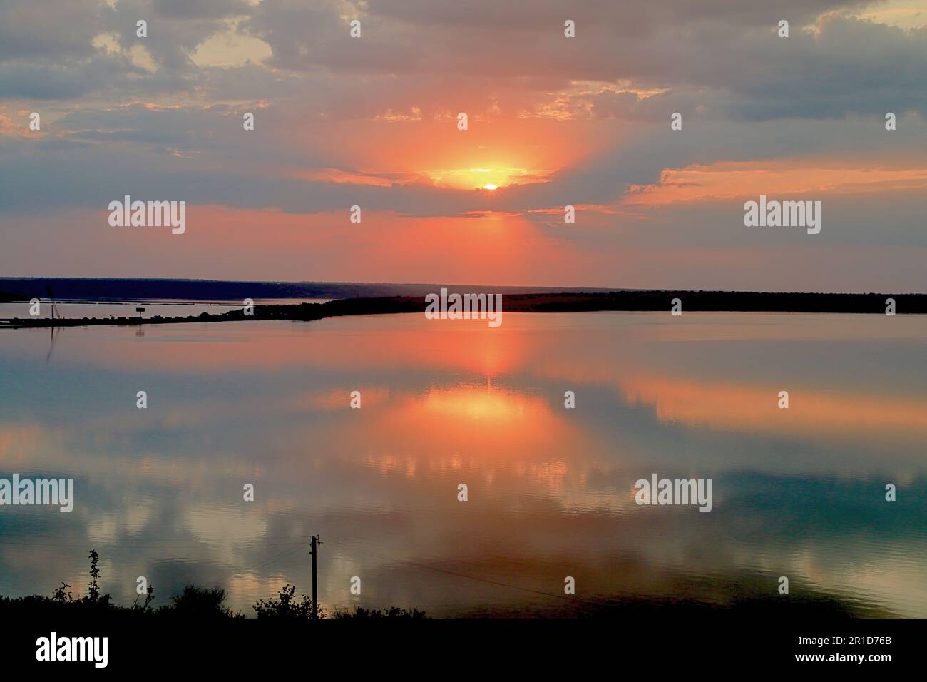 The photo was taken in Ukraine near the city of Odessa. The picture shows a sunset over a calm estuary reflecting the evening sky. Stock Photo