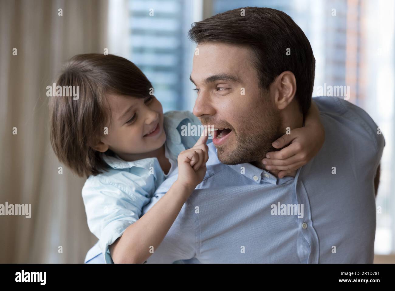 Positive handsome young father carrying cute little son on back Stock Photo