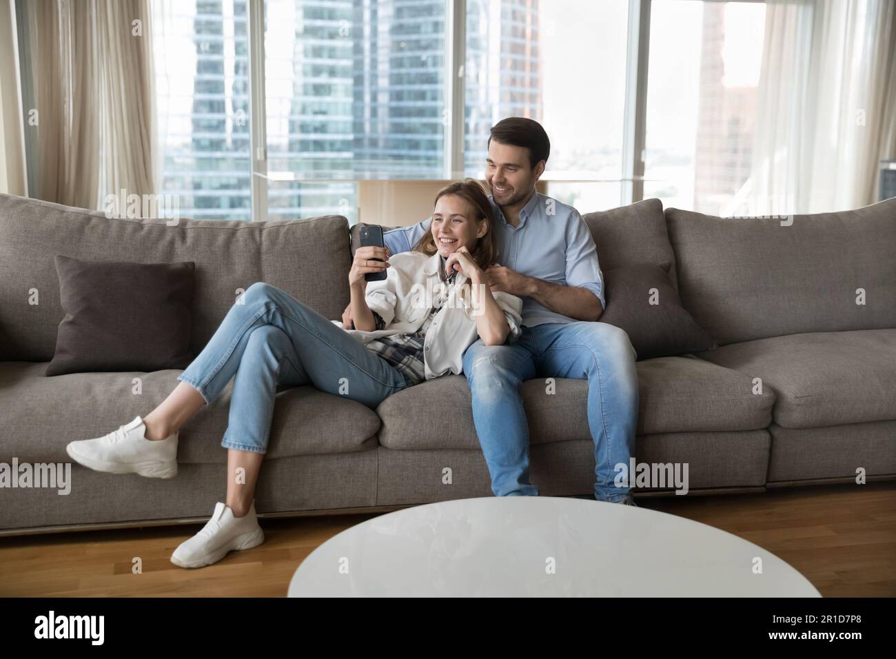 Happy young couple using mobile phone together Stock Photo