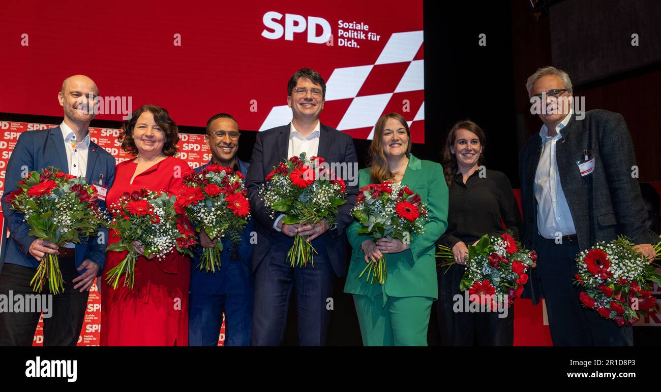 13 May 2023, Bavaria, Augsburg: The newly elected presidium of the Bavarian SPD Matthias Dornhuber (l-r), deputy party chairman, Ruth Müller, secretary general of the Bavarian SPD, Nasser Ahmed, deputy secretary general of the Bavarian SPD, Florian von Brunn, chairman of the Bavarian SPD, Ronja Endres, state chairwoman of the Bavarian SPD, Eva-Mairia Weimann, deputy party chairwoman, and Florian Ritter, treasurer of the Bavarian SPD, stand on stage with flowers at the party conference at the Kongress am Park. The agenda of the two-day party conference includes the election of the state executi Stock Photo