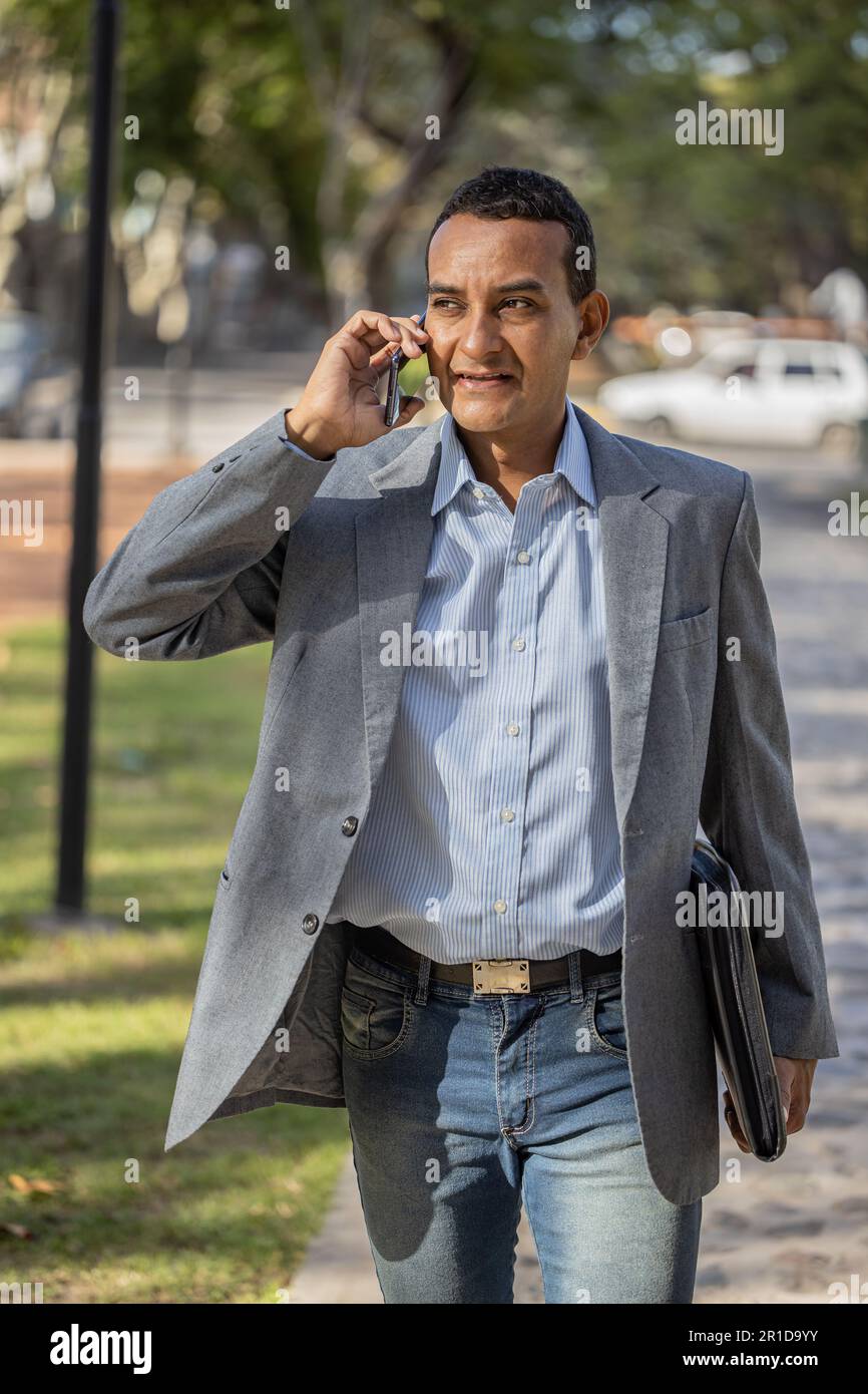 Latin young man in suit talking on mobile. Stock Photo