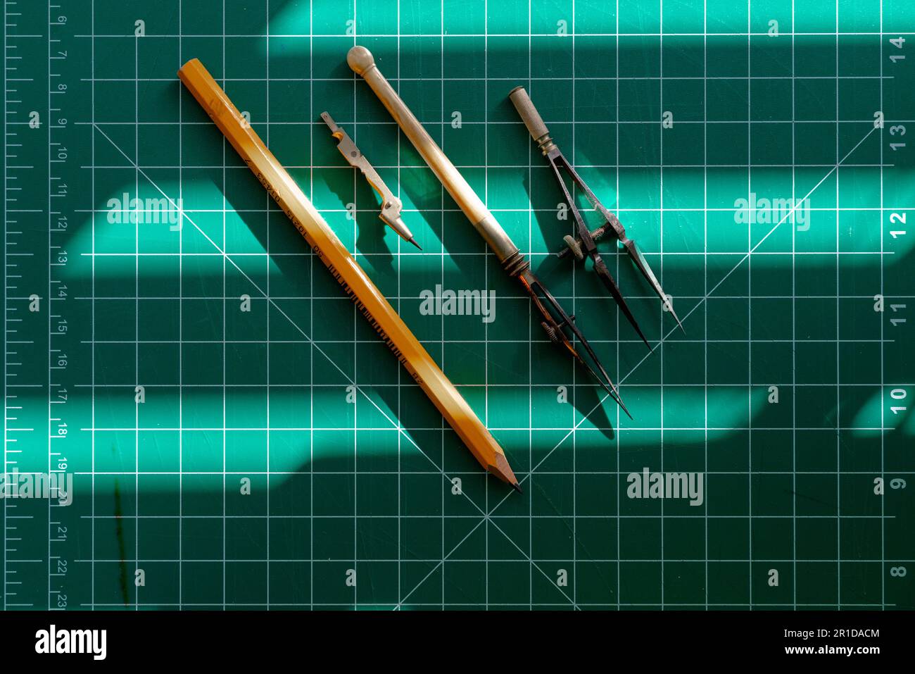 An assortment of vintage drawing instruments laid out on a cutting mat ...