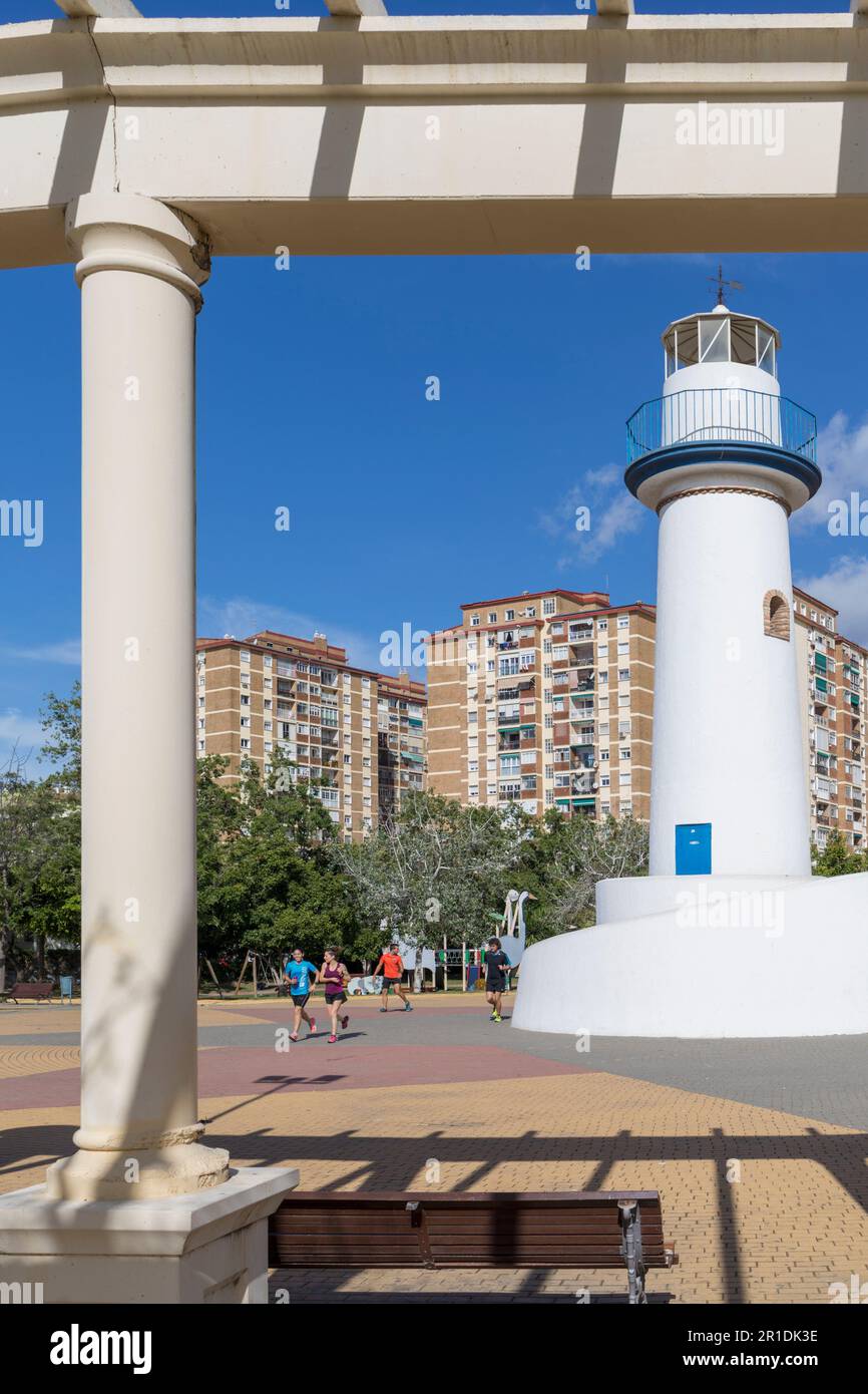 Runners passing the lighthouse in Parque de Huelin or Huelin Park, Malaga, Costa del Sol, Malaga Province, Andalusia, southern Spain.  Huelin is a bar Stock Photo