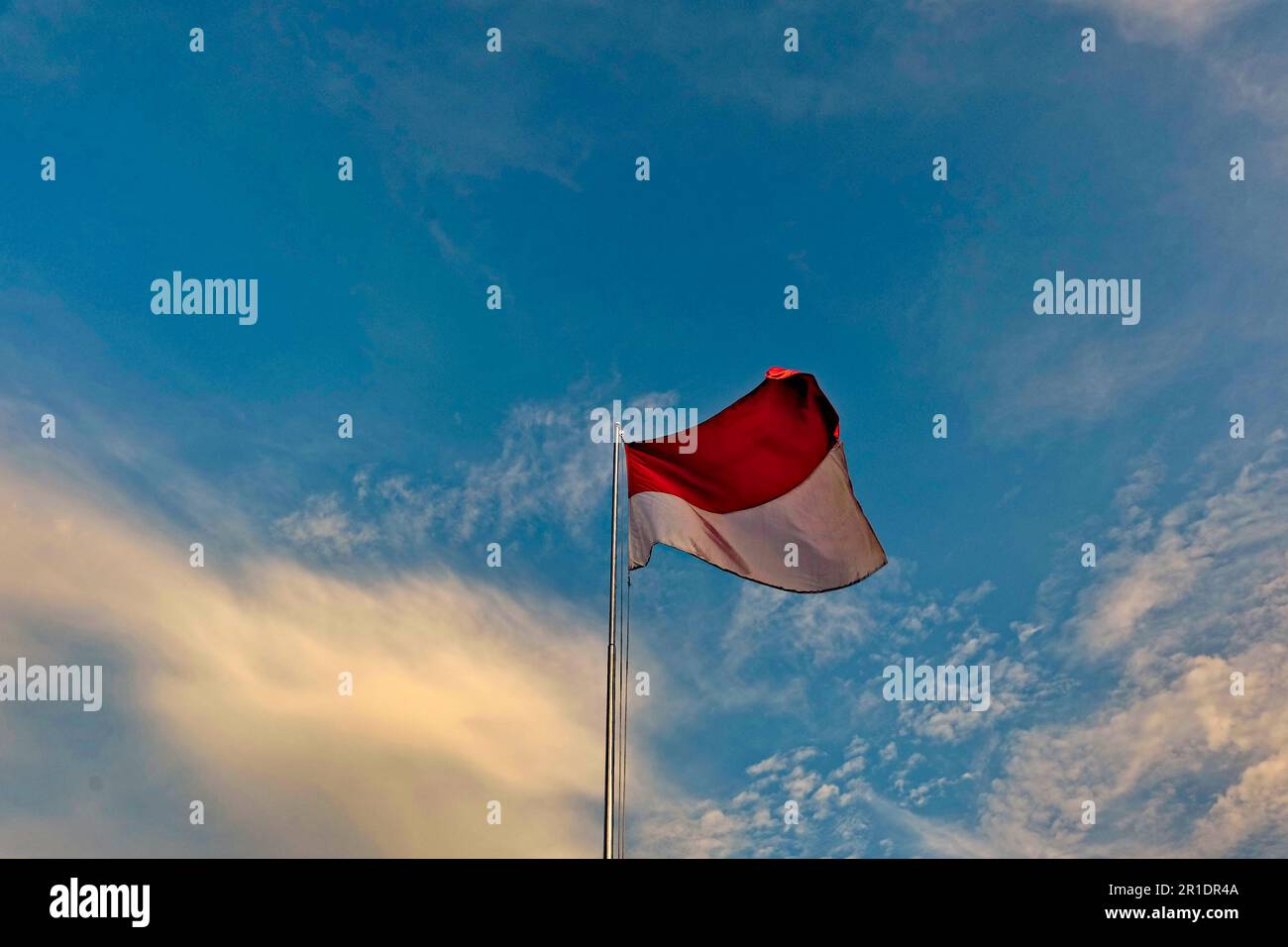 the red and white flagpole flutters against the sky, the Indonesian flag on the pole against the sky Stock Photo