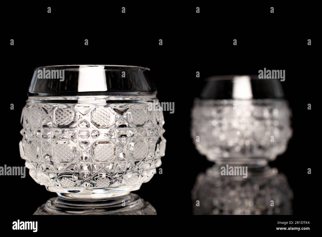 Two crystal glasses, macro, isolated on black background. Stock Photo