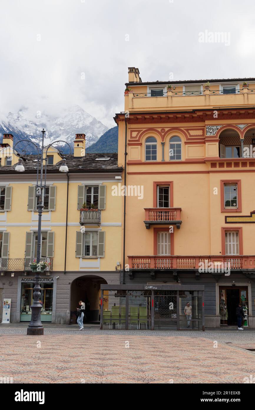 Buildings in Piazza Emile Chanoux, Aosta City, Aosta Valley, NW Italy. Snow covered alps behind. Stock Photo