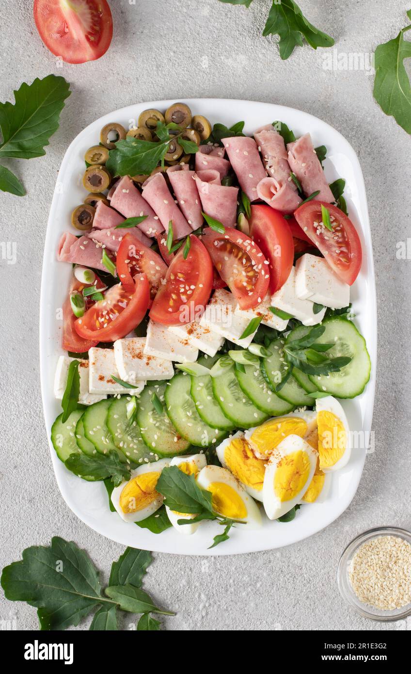 Healthy cobb salad with ham, feta cheese, cucumber, tomato, olives and