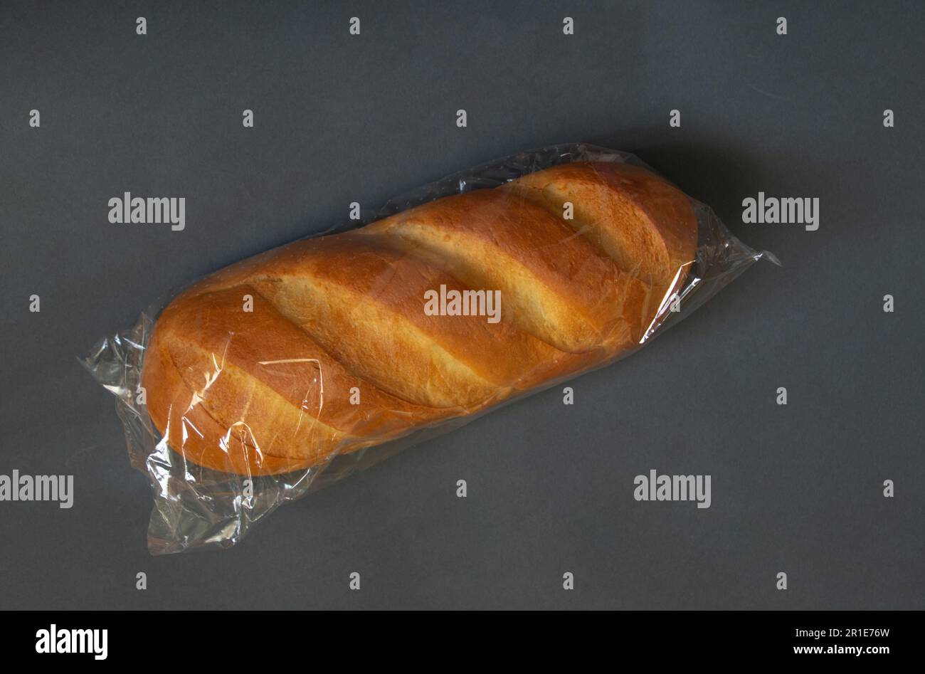 loaf of white bread in packaging on a dark isolated background close-up Stock Photo
