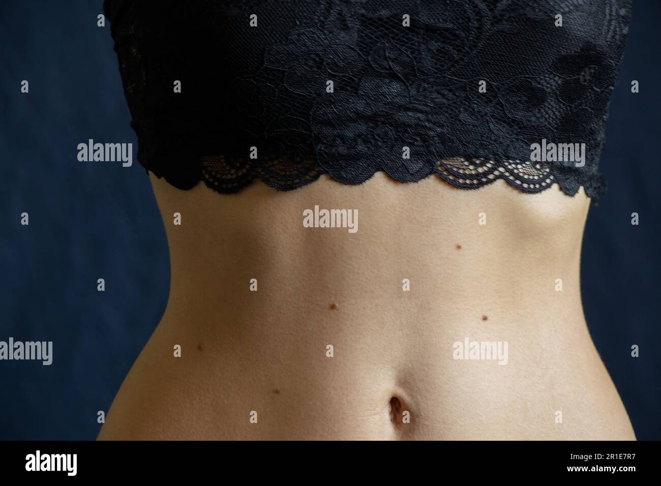 navel and belly of a young girl close up on a dark background Stock Photo