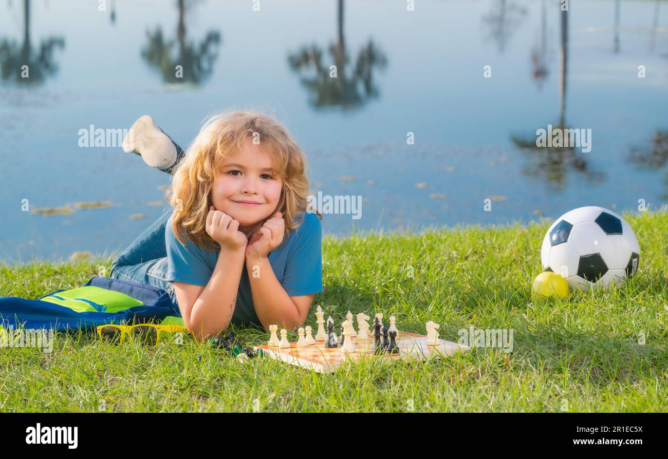 Little child chessman play chess game, checkmate. Child playing chess in spring park Stock Photo