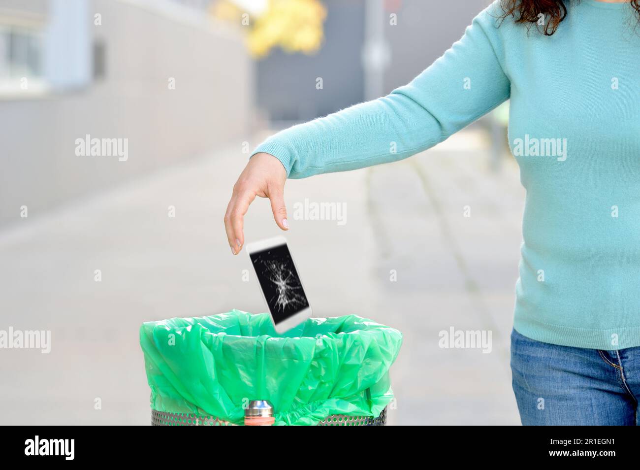Woman throwing her broken phone into the garbage in a trash bin at
