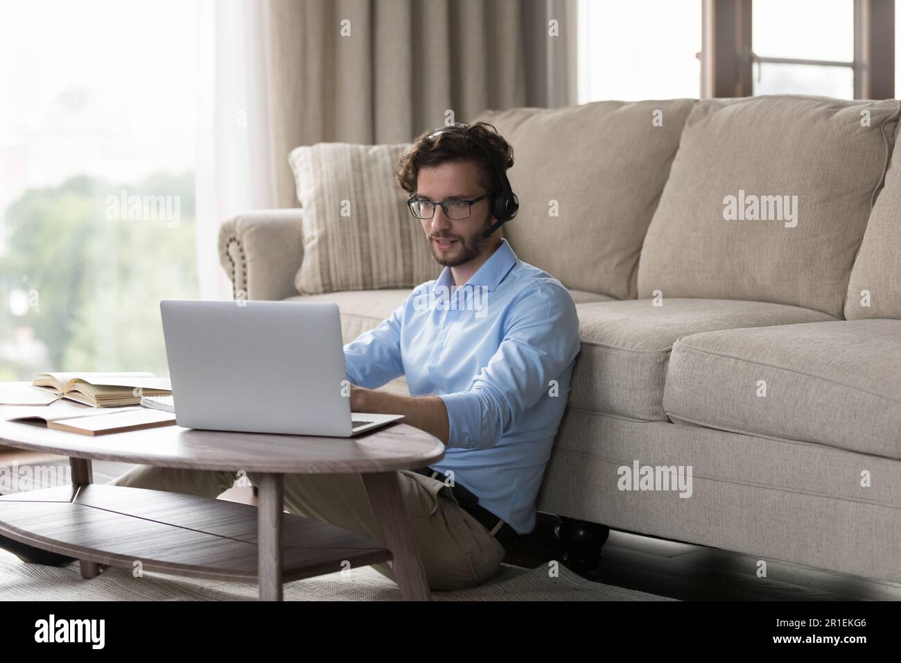 Focused positive student man in wireless headset using laptop Stock Photo