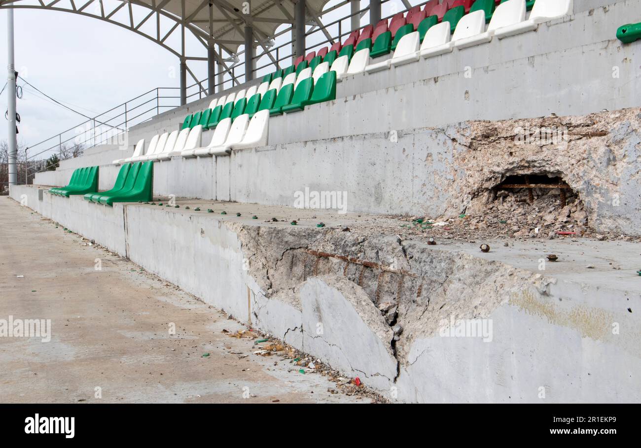 War in Ukraine. Broken plastic benches for fans on the podium, in a destroyed football stadium in a children's football school. The consequences of sh Stock Photo