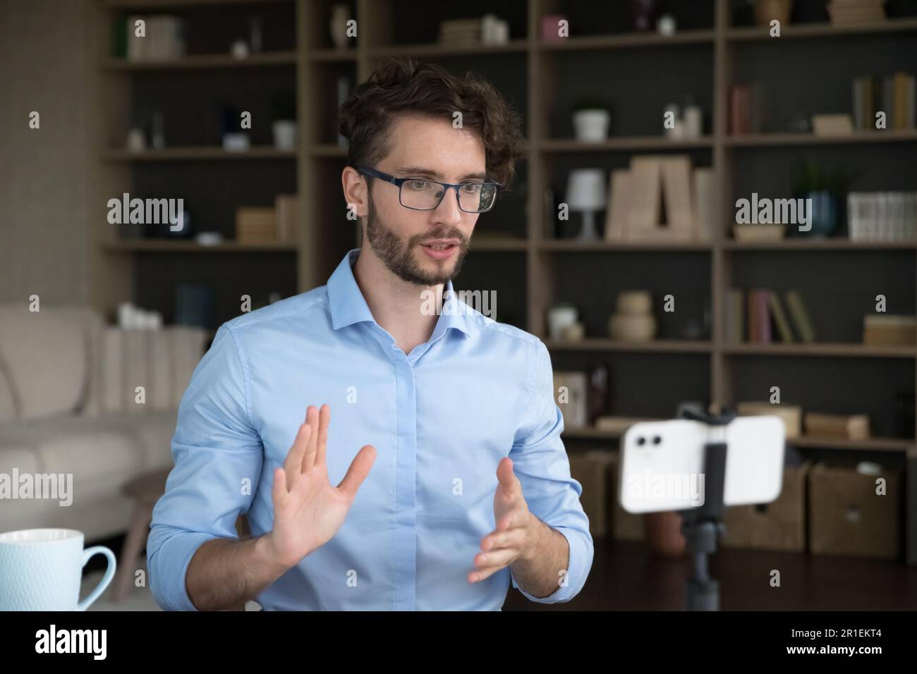 Handsome young business influencer in stylish eyeglasses streaming on Internet Stock Photo