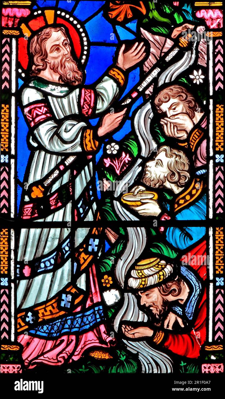 Moses strikes rock, with stick, water flows from rock, men drink the water, Bible story, Biblical, stained glass, Snettisham, Norfolk Stock Photo