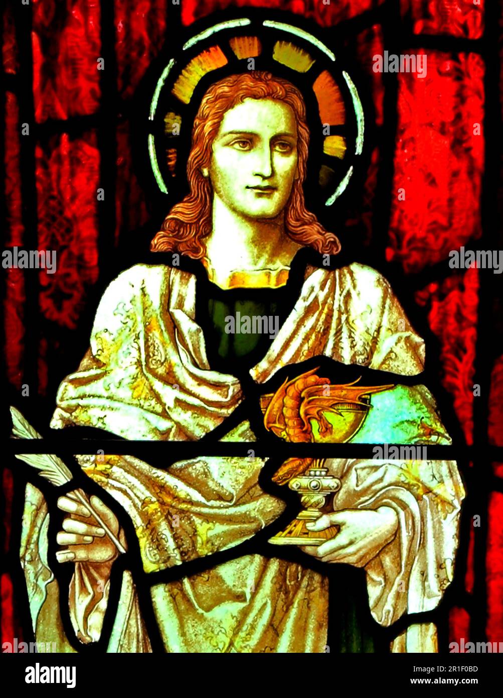 Saint John, holding wine cup, chalice, with snake, stained glass window, Snettisham church, Norfolk, England Stock Photo