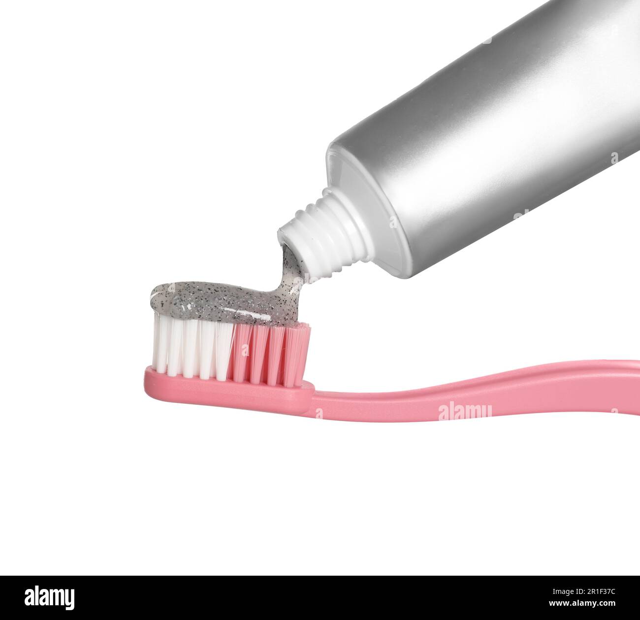 Applying charcoal toothpaste on brush against white background Stock Photo