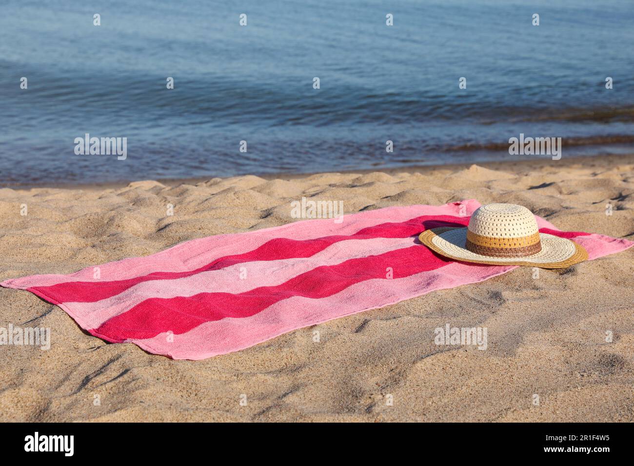 Beach towel and straw hat on sand near sea Stock Photo - Alamy
