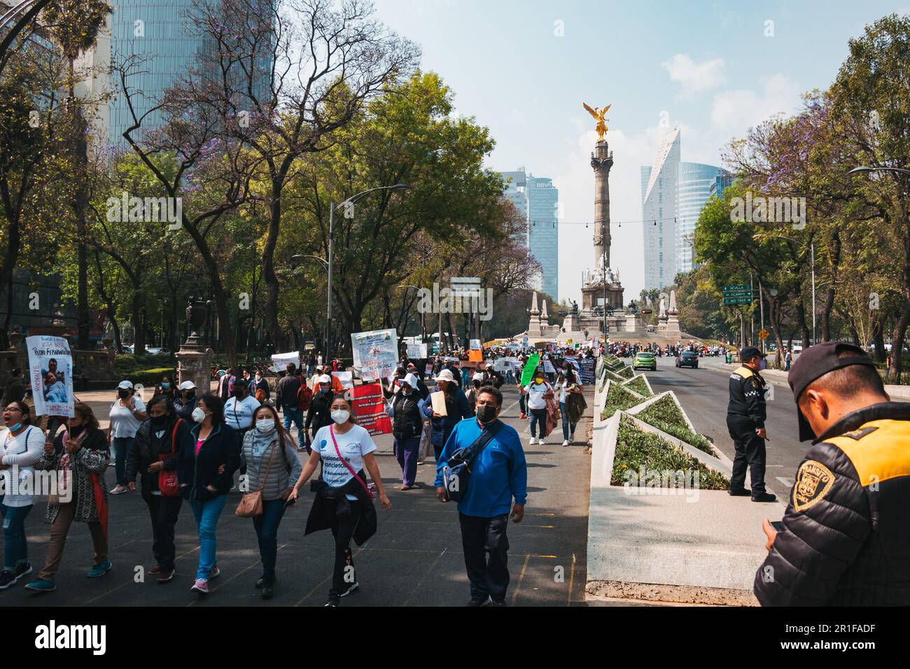 Protestors march down Av. Paseo de la Reforma in Mexico City, Mexico. The golden Angel of Independence statue can be seen behind Stock Photo