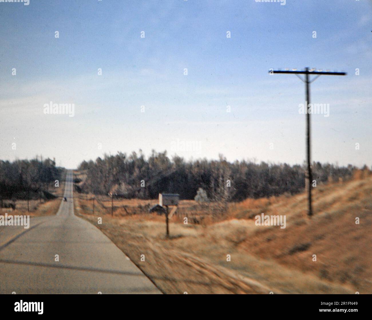 View of a car in the distance on a rural highway and a mailbox on the