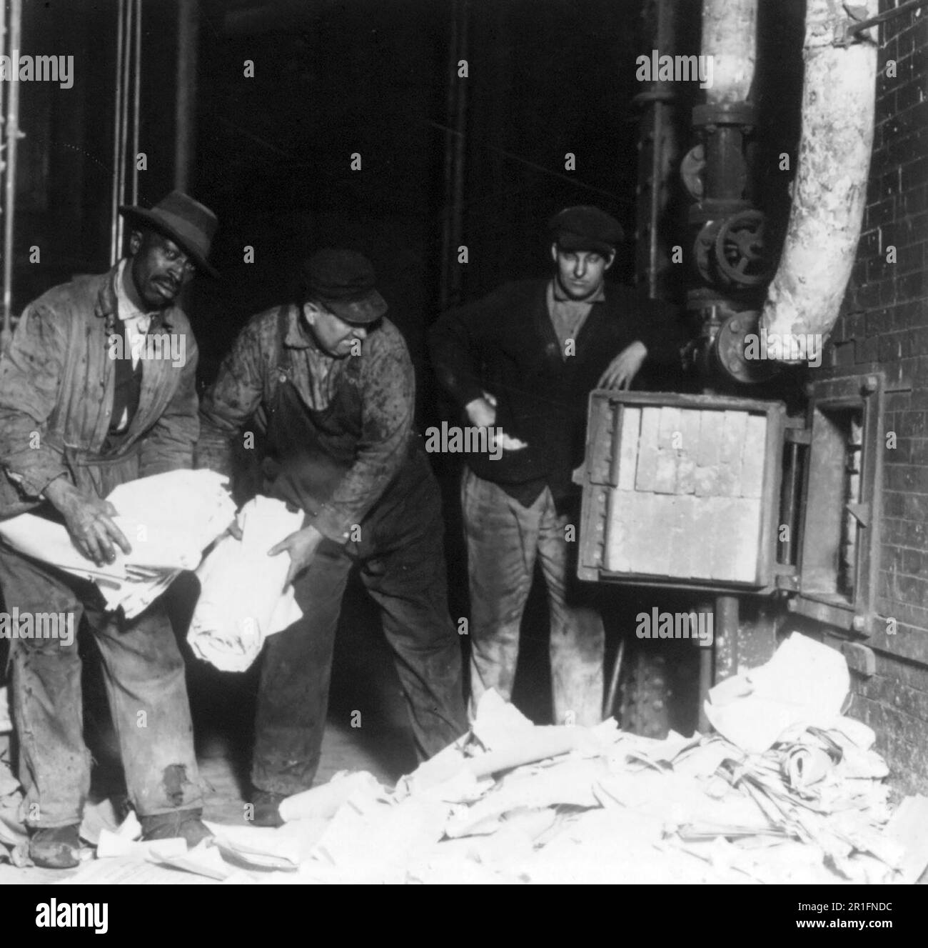 Archivial Photo: Three men throwing ballots, tally sheets and poll books of the Newberry election of 1918 into furnace at the U.S. Capitol Power House - they were ordered to be burned by Federal Judge Tuttle of Detroit ca. 1923 Stock Photo