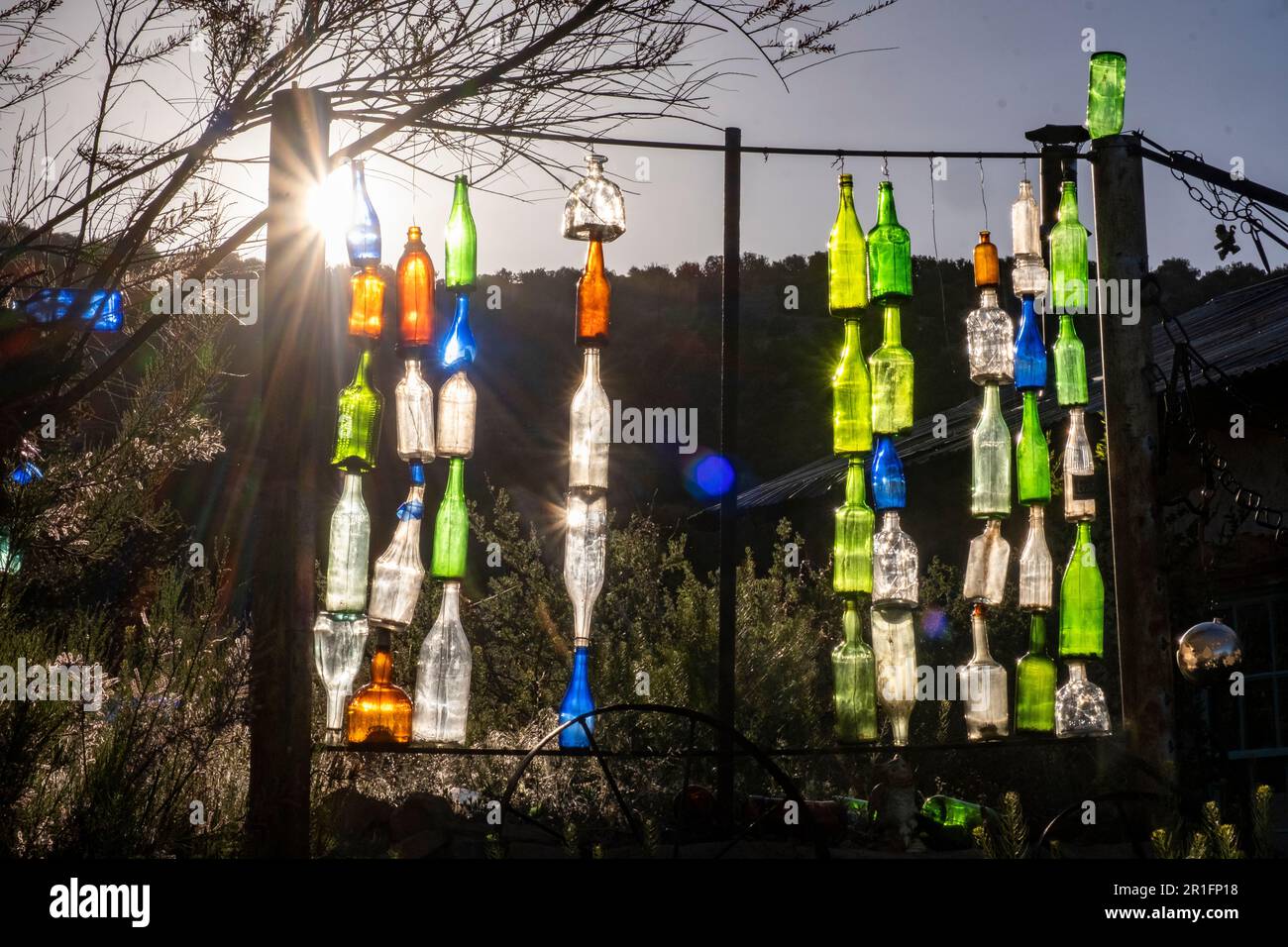 Colored bottles glowing in the evening sun at the Golden Bottle House, Golden, New Mexico, USA Stock Photo