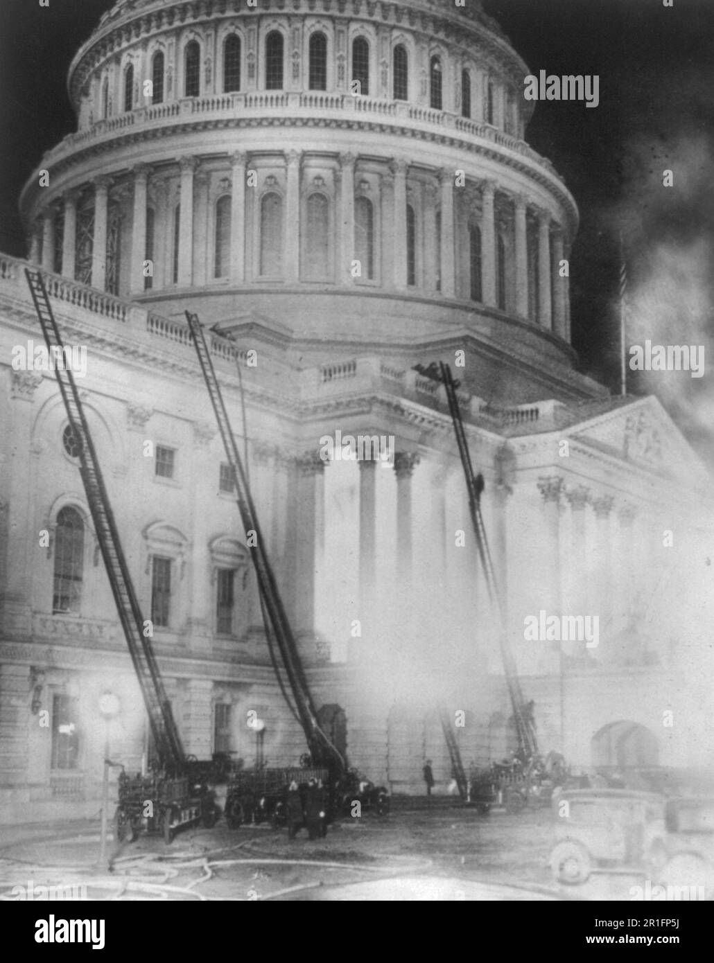 Archivial Photo: View of the U.S. Capitol during the fire which destroyed the studio of Artist Chas. Moberly & considerably damaged the House Document Room - fire engines with ladders going up the side of the Capitol ca. 1930 Stock Photo