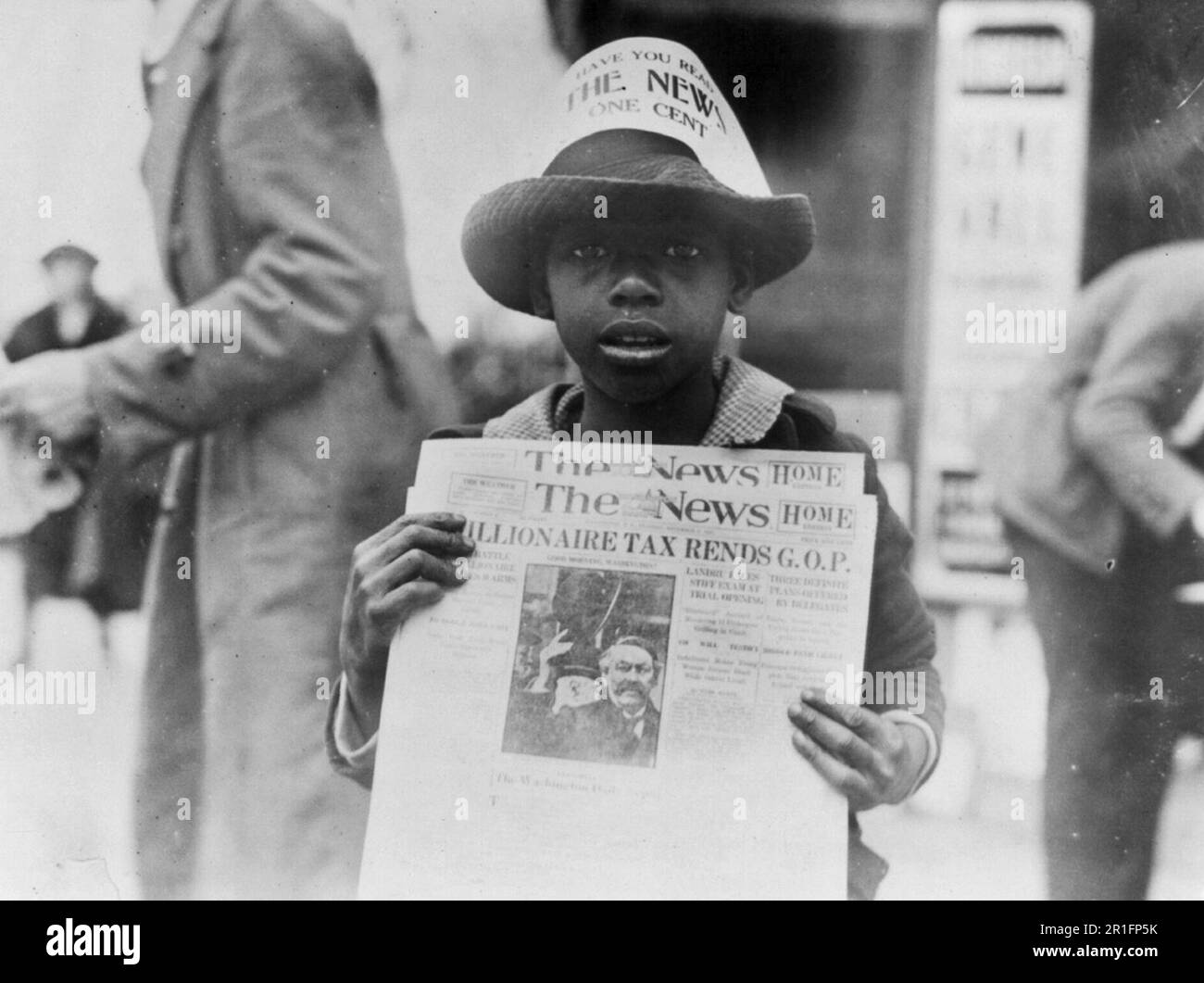 Archival Photo: African American boy selling The Washington Daily News - sign on his hat reads, 'Have you read The News? One cent' - headline reads 'Millionaire tax rends G.O.P.' ca. 1921 Stock Photo