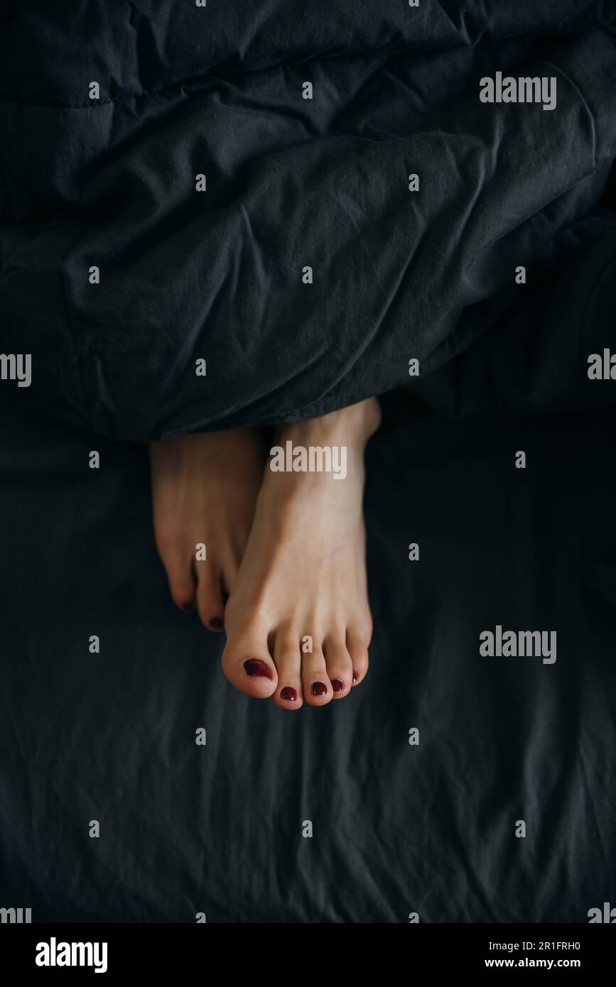 Women's legs stick out from under the covers in bed Stock Photo - Alamy