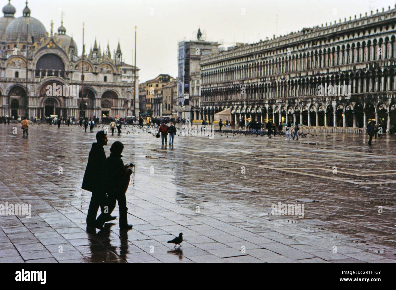 A husband and wife walking through Piazza San Marco on a rainy day - Venice ca. 2000 Stock Photo