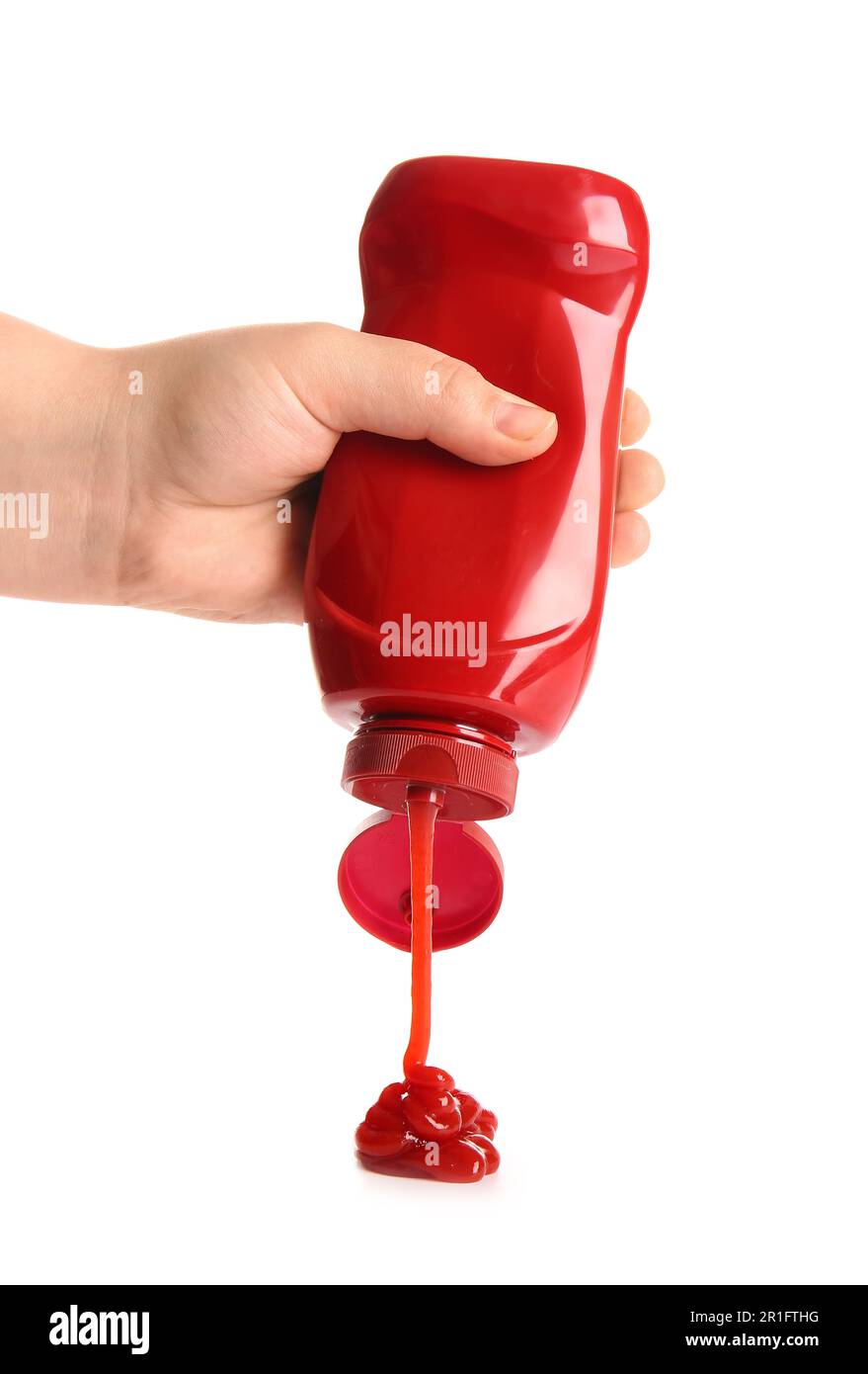 Hand holding ketchup bottle upside down and squeezing on white