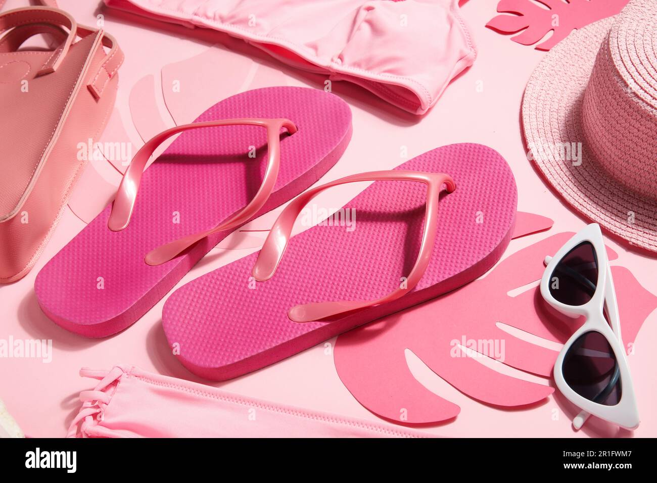Flip flops with sunglasses, swimsuit, bag and wicker hat on pink ...