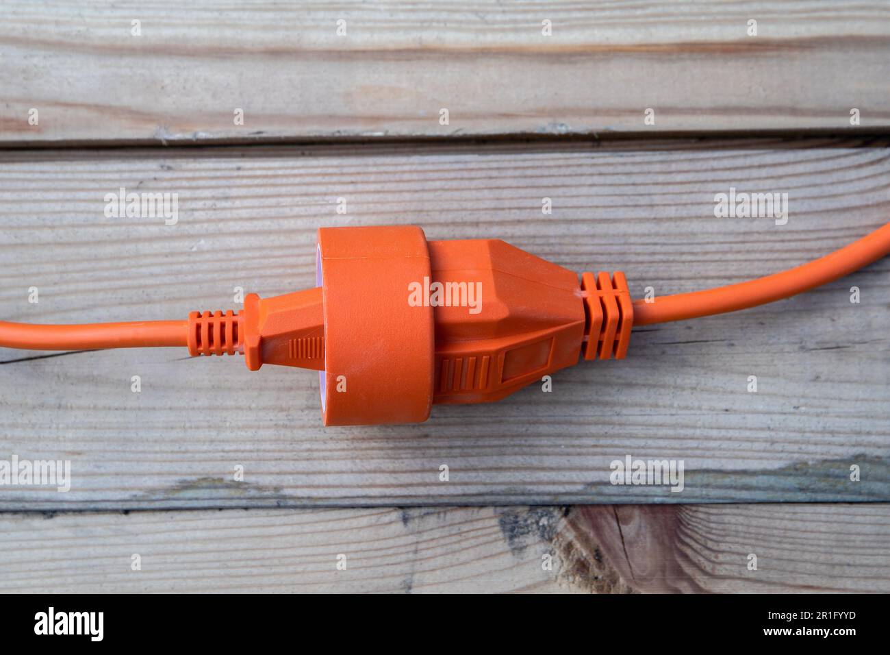 Orange electric wire, cable or extension cord on wood texture