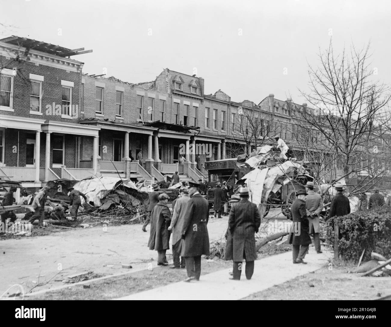 Archival Photo: Men watching debris being cleaned up at row houses on A St., NE, near 14th St., Washington D.C., severely damaged by a tornado on Nov. 17, 1927 Stock Photo