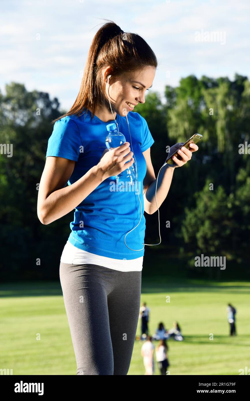 Young women reading sms message on her smartphone in the park Stock Photo
