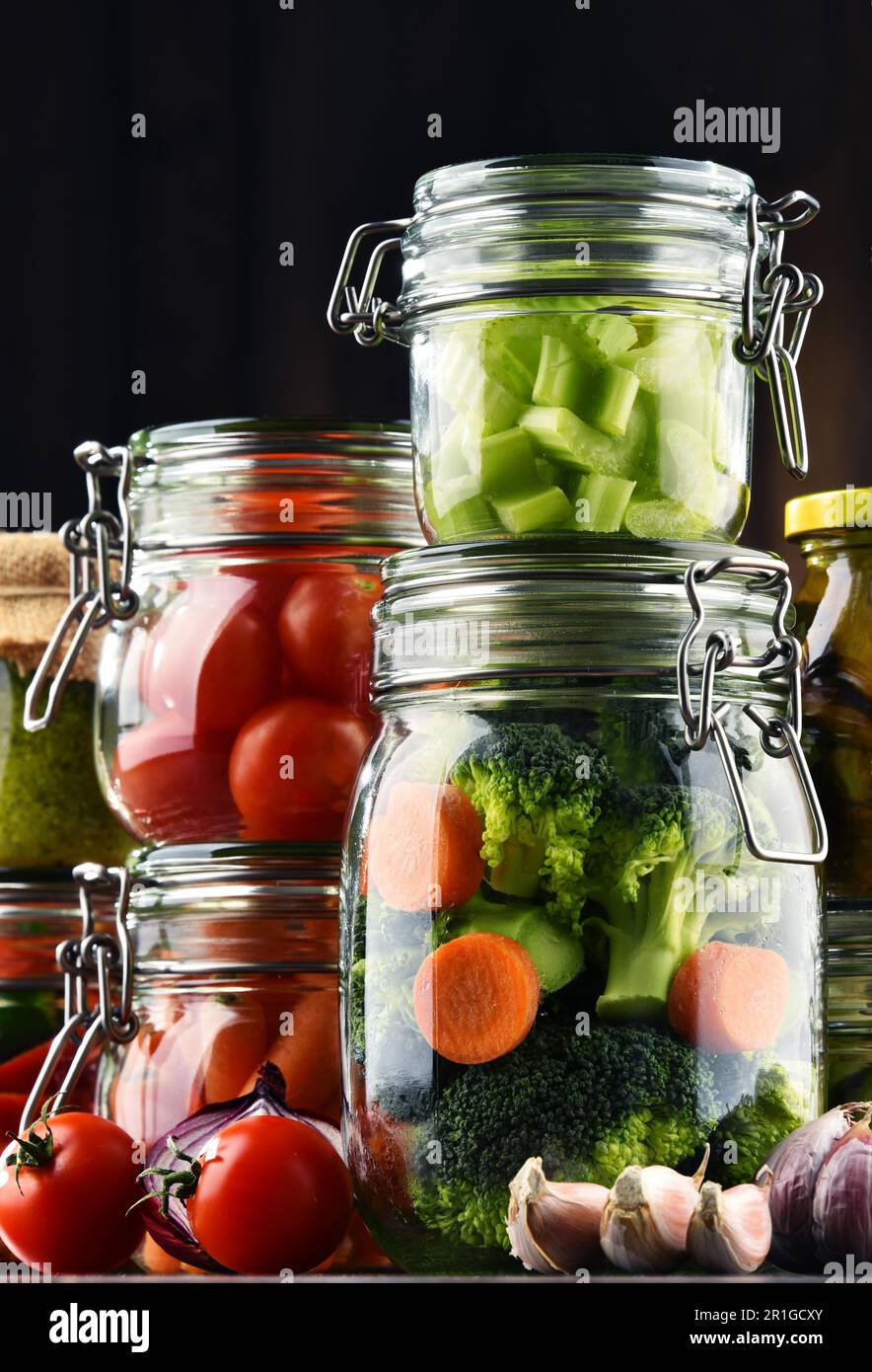 Jars with marinated food and organic raw vegetables Stock Photo