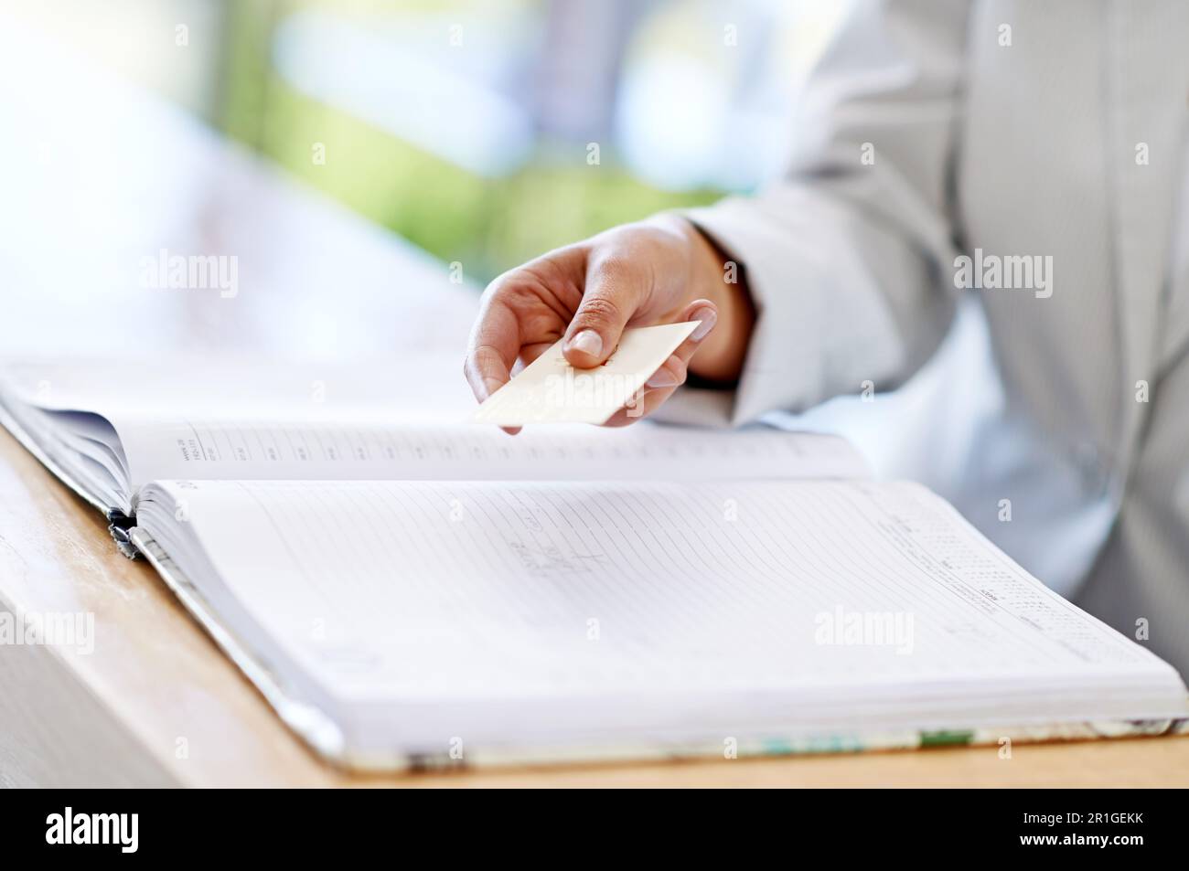 Woman, hands and credit card with book for payment, transaction or purchase for appointment or reservation. Hand of female showing debit at reception Stock Photo
