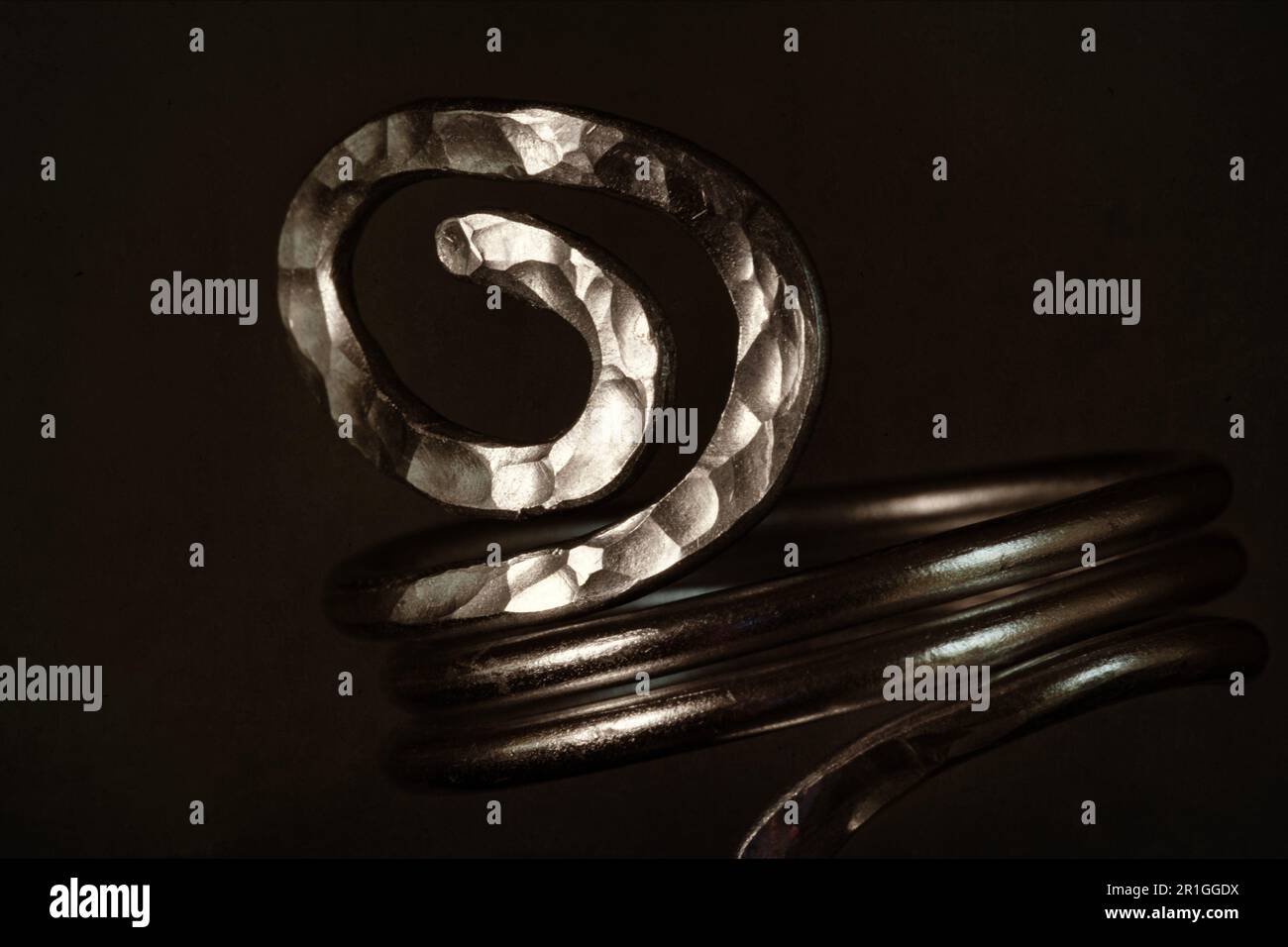 Close up of a home made metal wire ring, shaped into a spiral and worked to create texture. Stock Photo