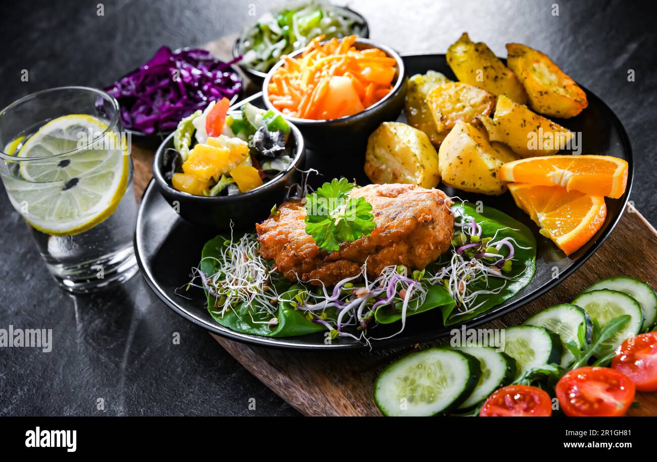 Pulled chicken cutlet coated with breadcrumbs with potatoes and vegetable salads Stock Photo