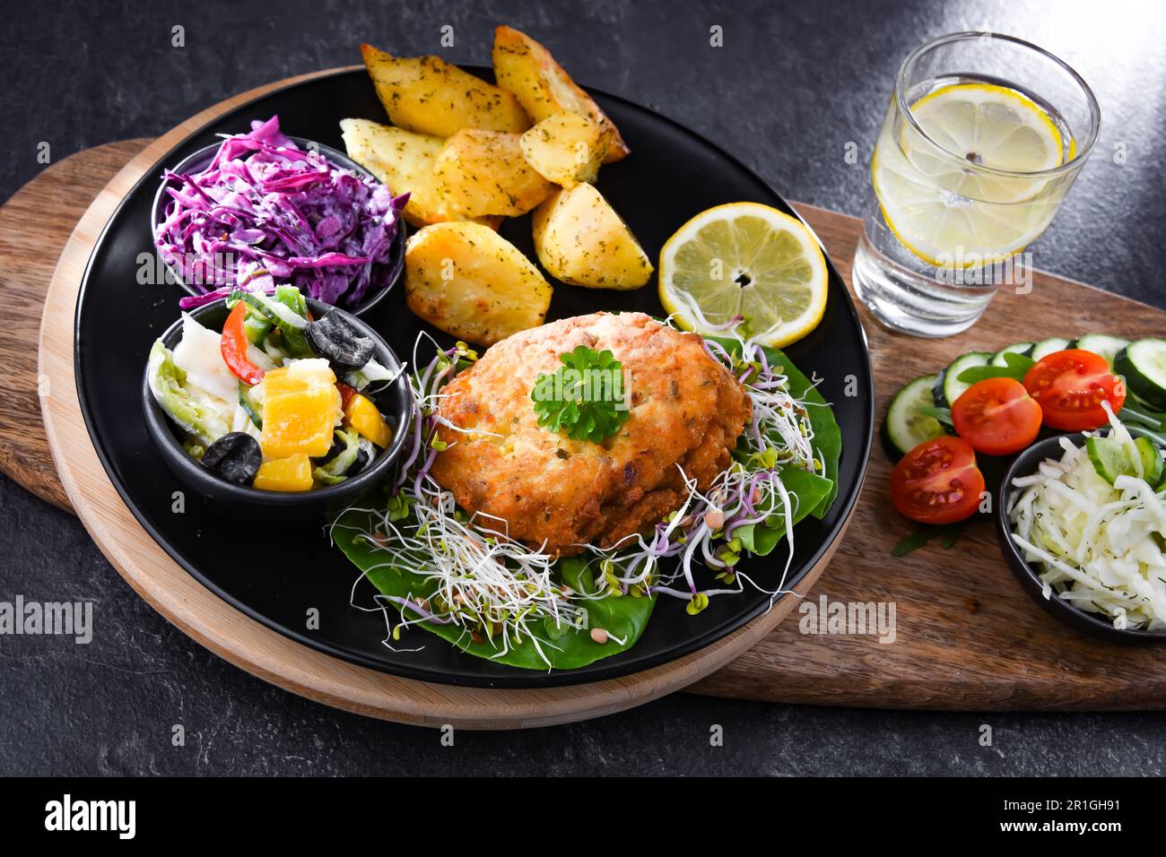 Pulled chicken cutlet coated with breadcrumbs with potatoes and vegetable salads Stock Photo