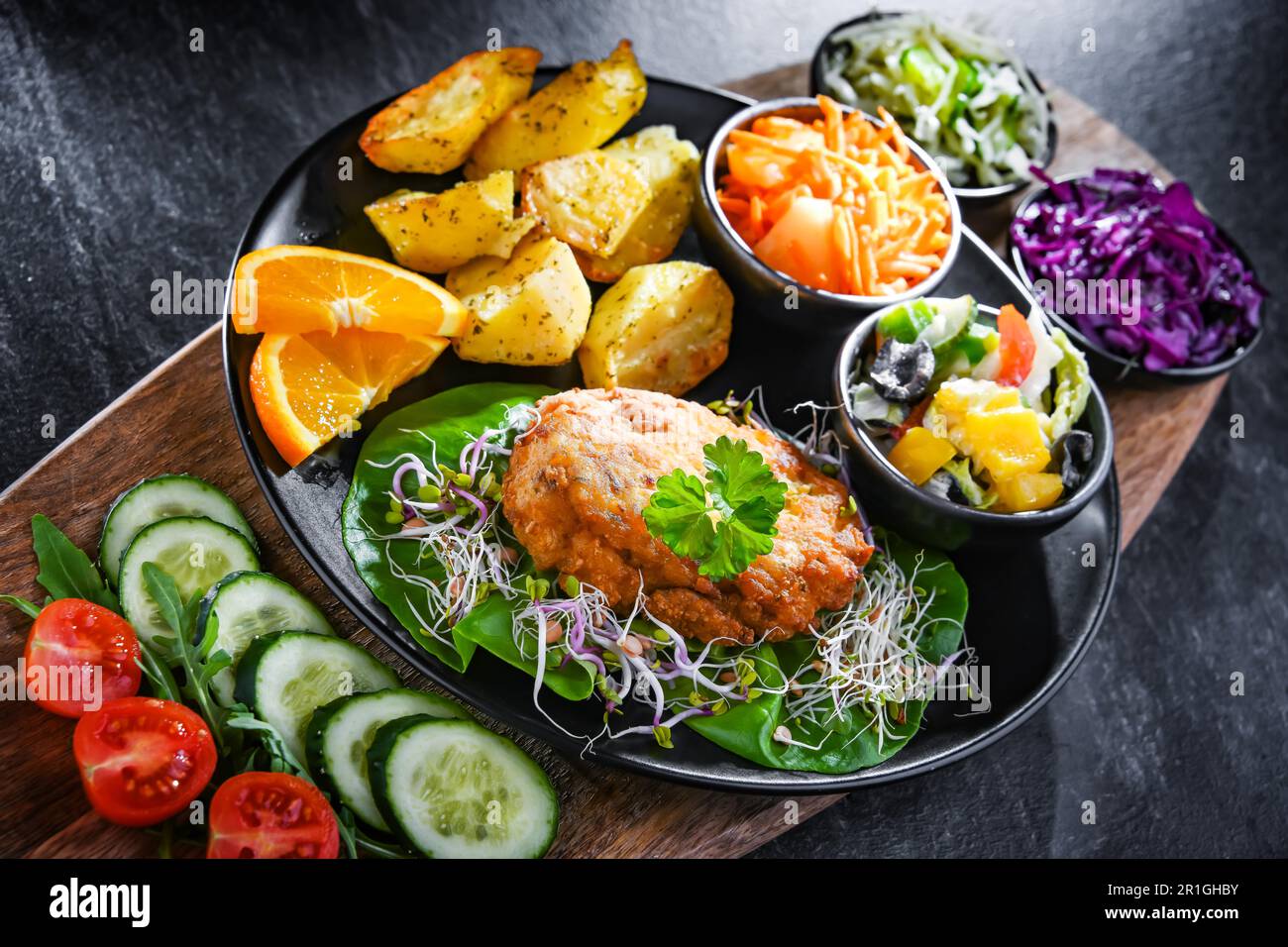 Pulled chicken cutlet coated with breadcrumbs with potatoes and vegetable salads Stock Photo