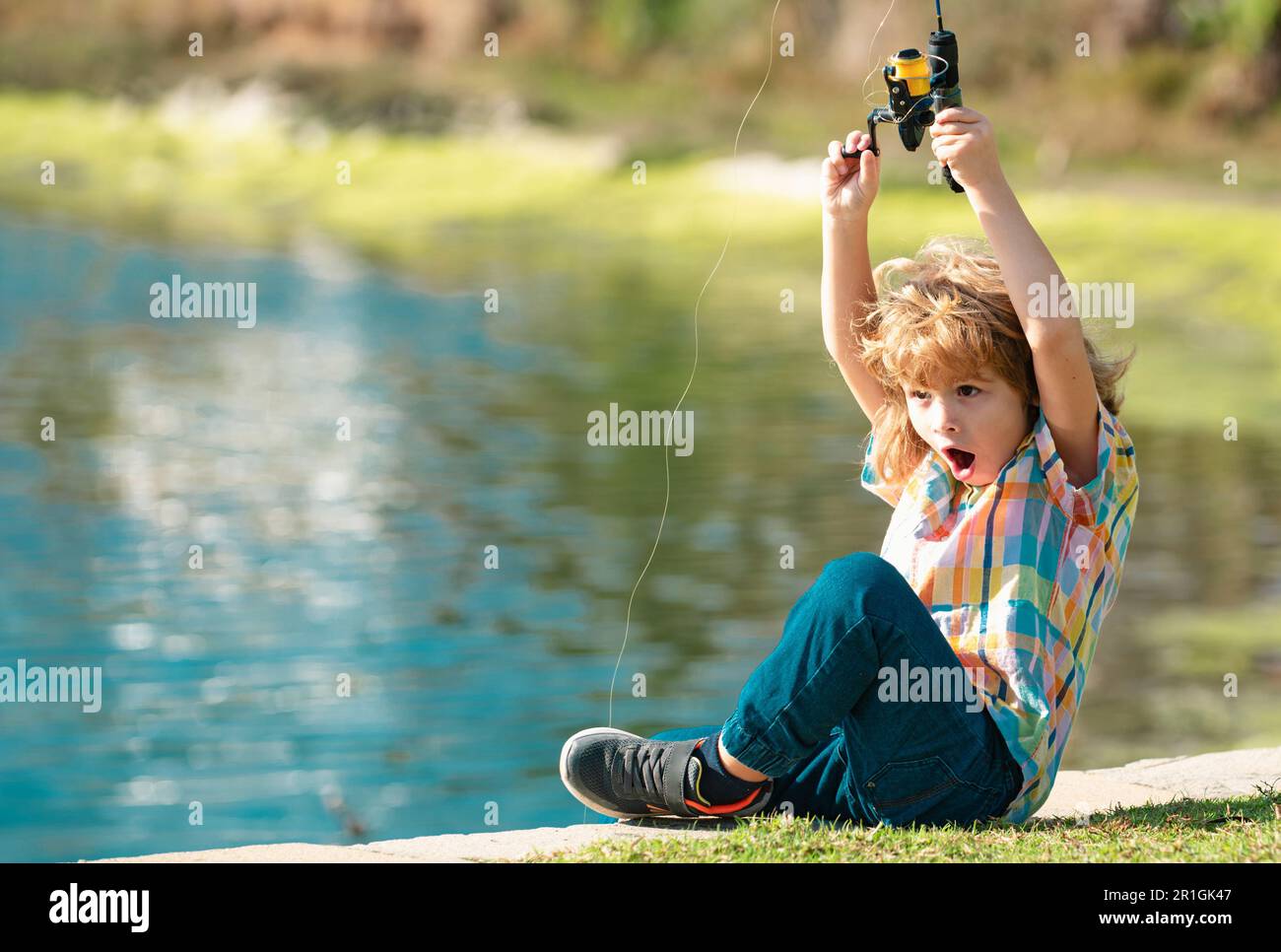 Funny happy little kid fishing on weekend. A fisherman boy stands