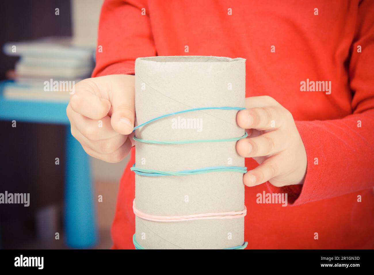 Little boy putting rubber colorful bands or erasers on cardboard roll
