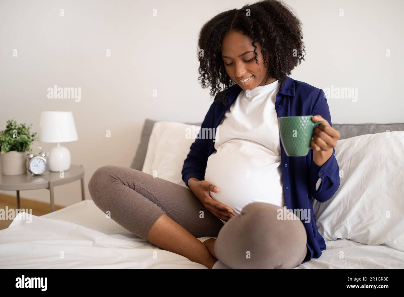 Happy millennial african american pregnant lady with big belly drinks ...