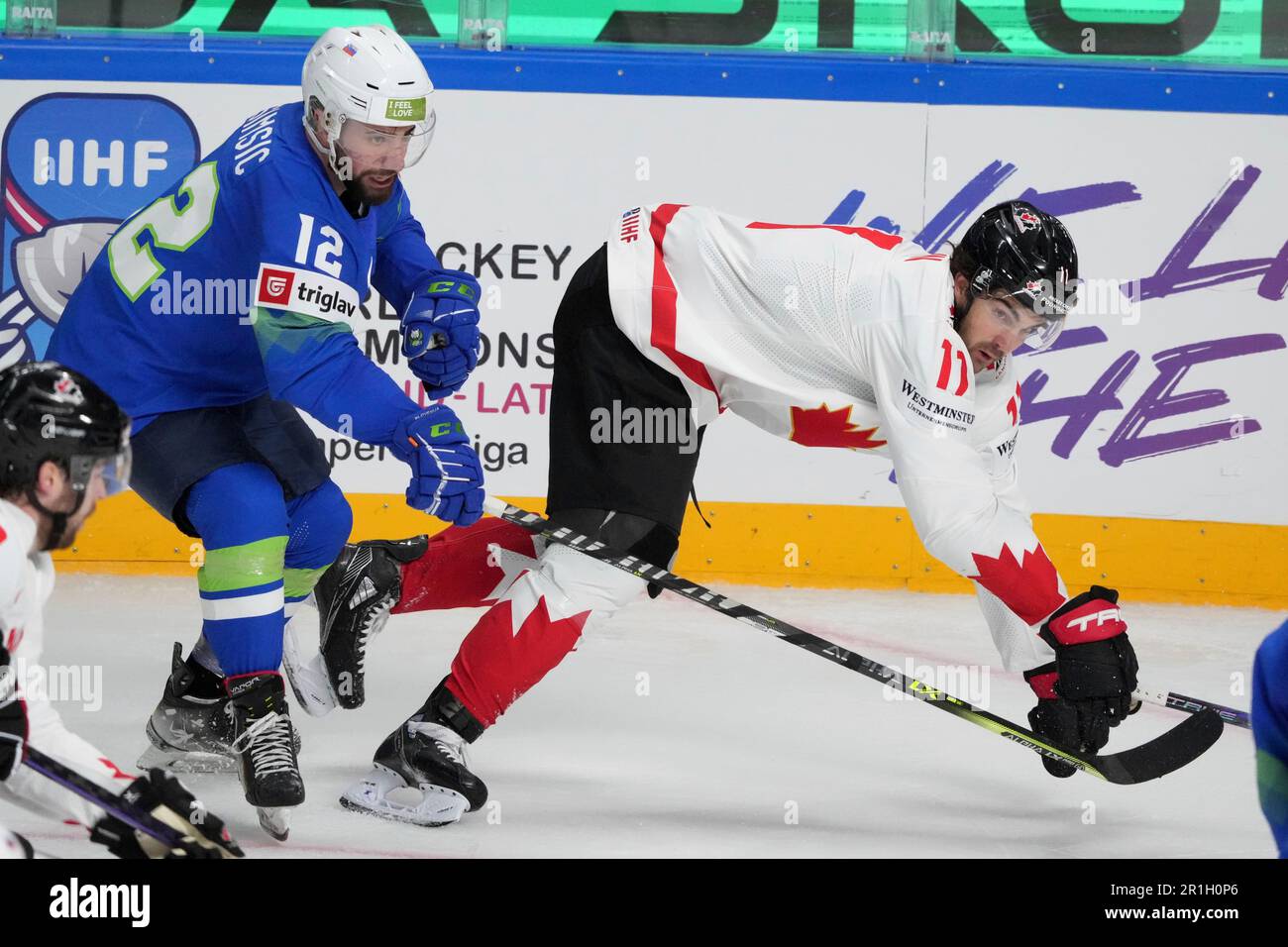 Nik Simsic of Slovenia, left, fights for a puck with Jack McBain of Canada  during the group B match between Slovenia and Canada at the ice hockey  world championship in Riga, Latvia,