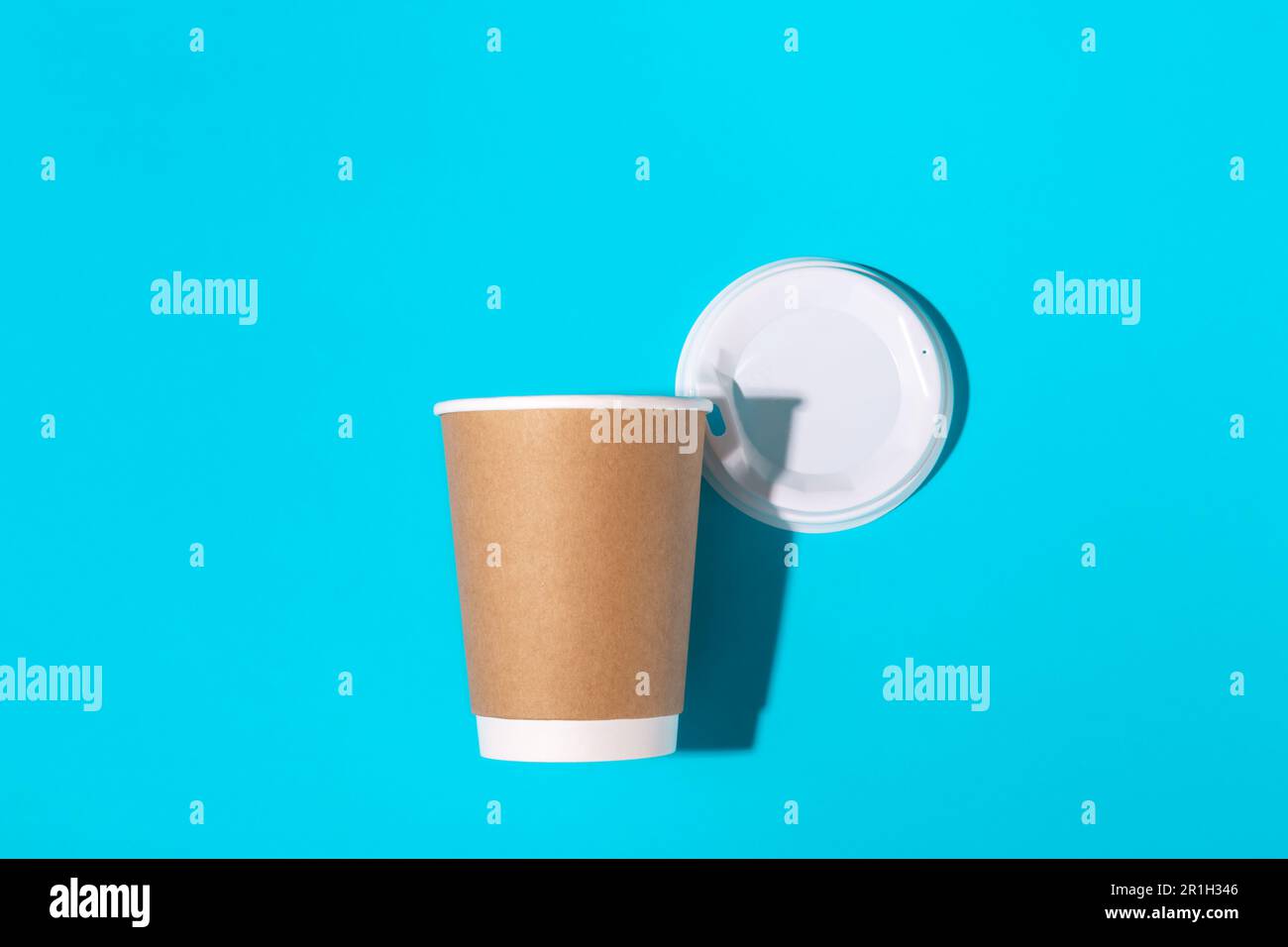 Disposable paper cup with a dark shadow on a blue background, top view ...